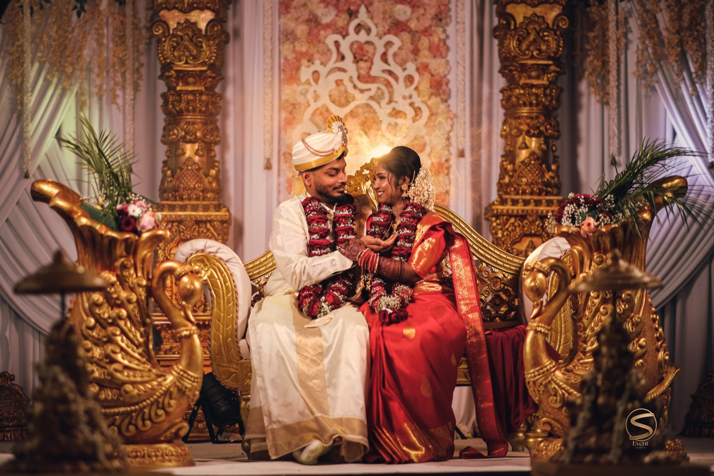Brautpaar auf einer goldenen Hochzeitsbühne mit Schwanenthron, gestaltet von Event by Sakthys