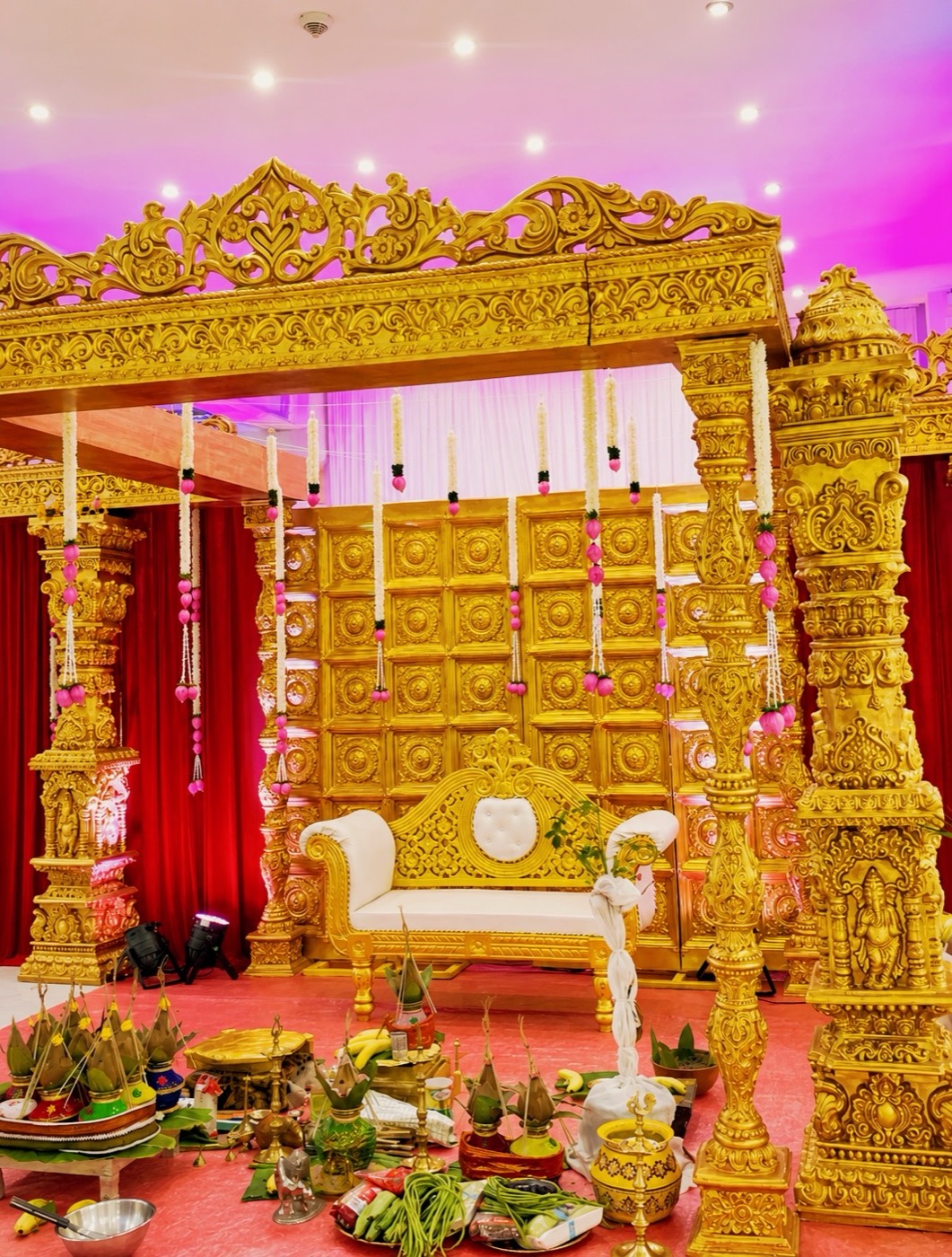 Detail eines goldenen Mandapams mit Jasminsträngen und Puja-Gaben